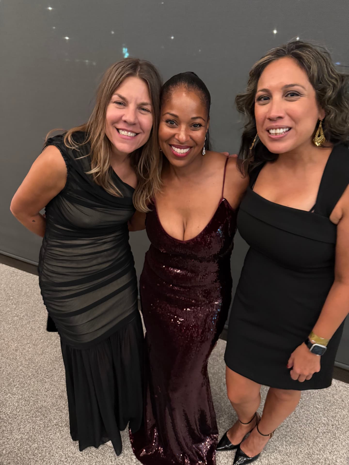 Three friends in evening wear smiling together