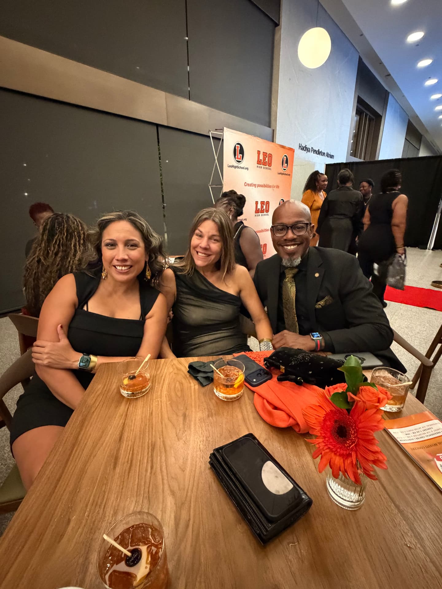 Three guests smiling at a reception table in front of the Leo backdrop