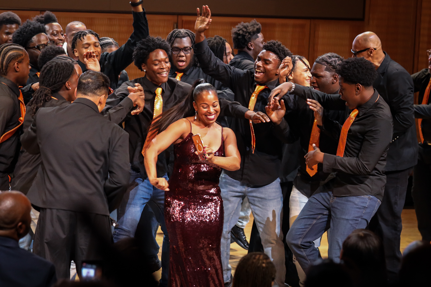 Choir members dancing and celebrating around a guest in a sequined gown