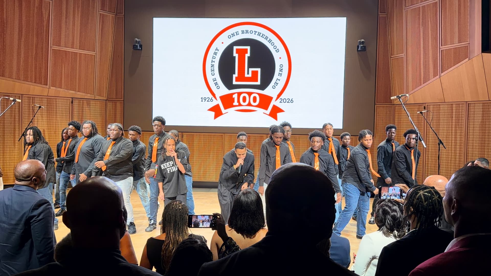 The choir dancing behind two guest vocalists on stage
