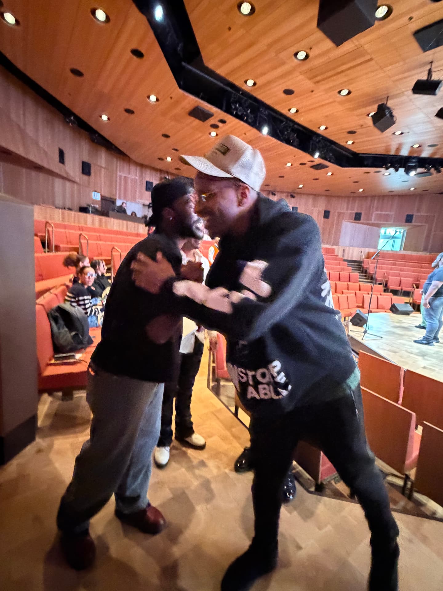 Two men embracing in the auditorium during rehearsal