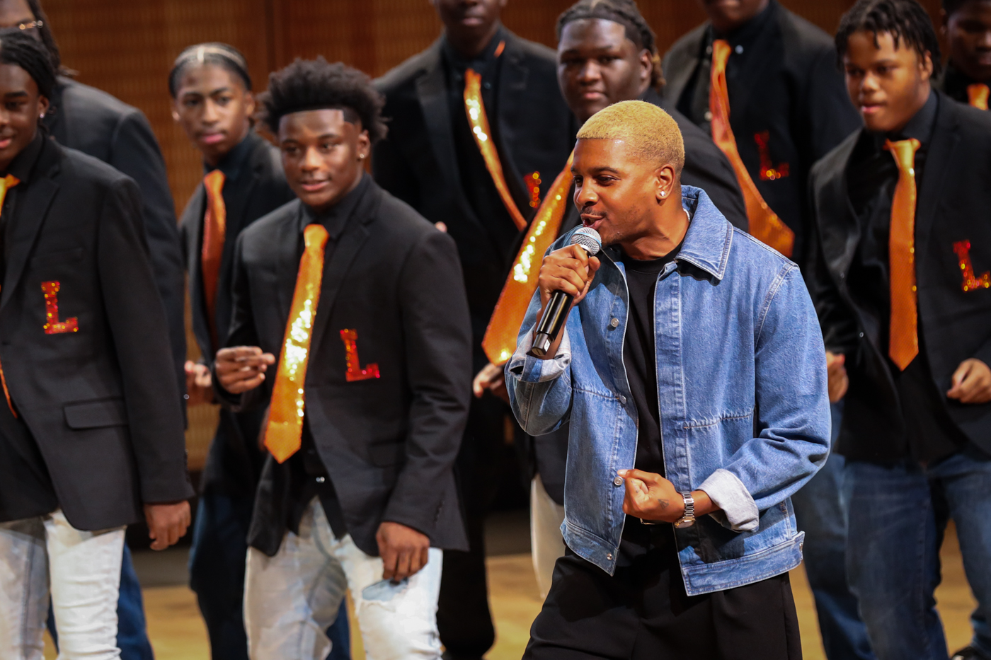 A guest vocalist in a denim jacket singing in front of the choir