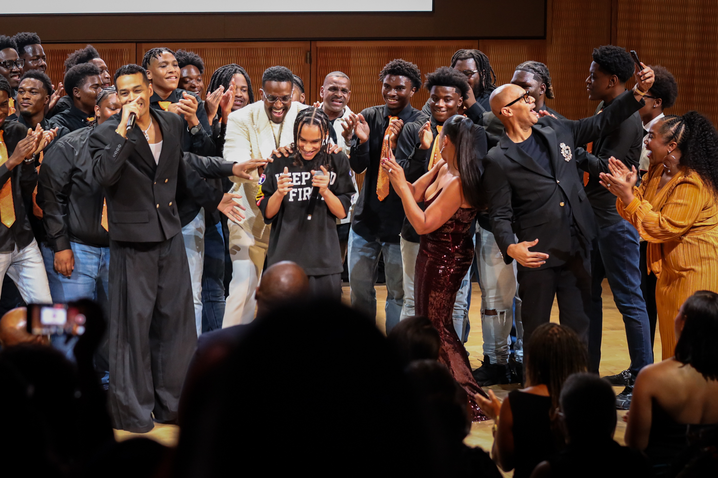 The choir and guests cheering around a young performer at center stage