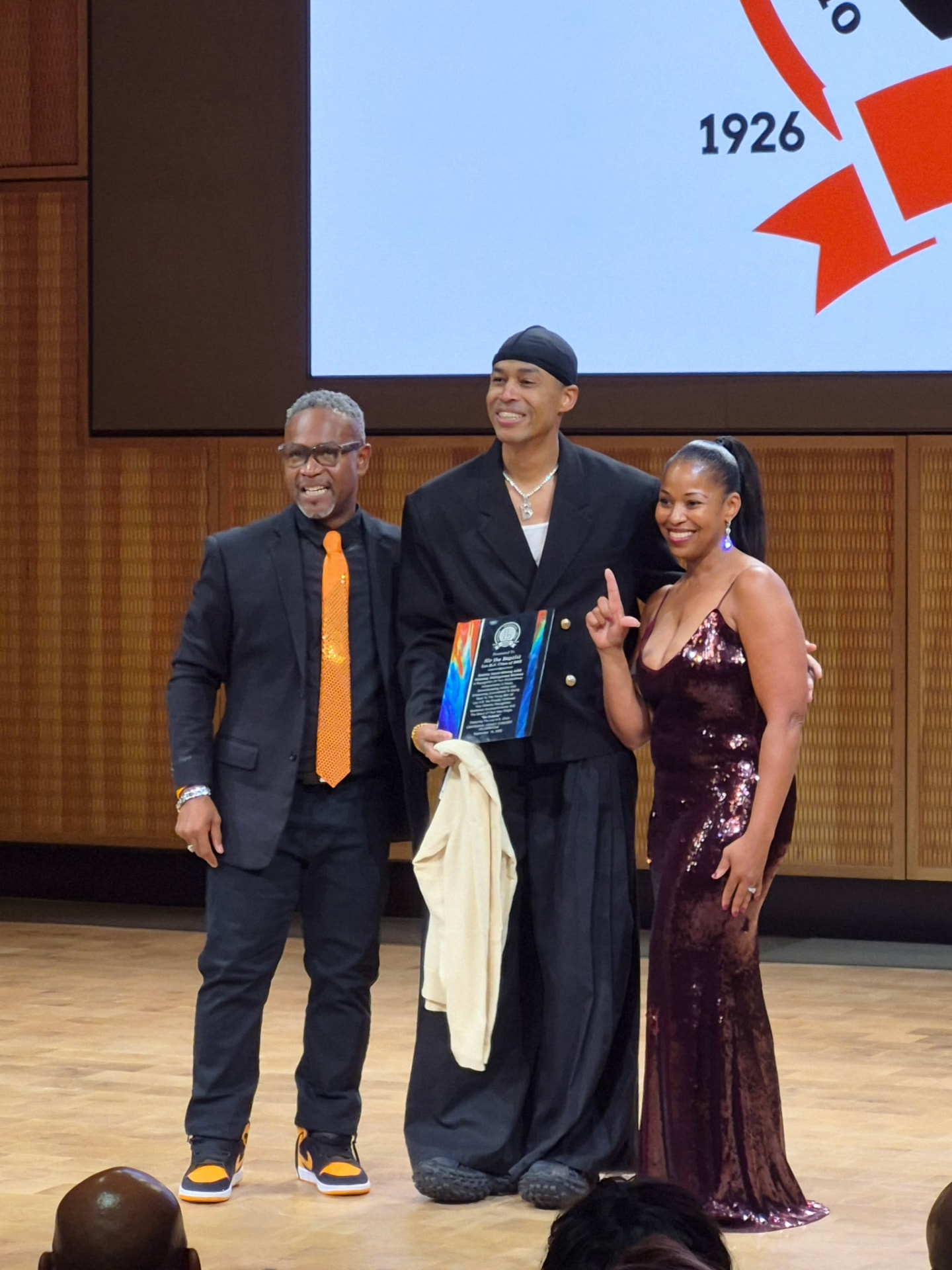 An honoree holding an award on stage beneath the Leo 100 logo