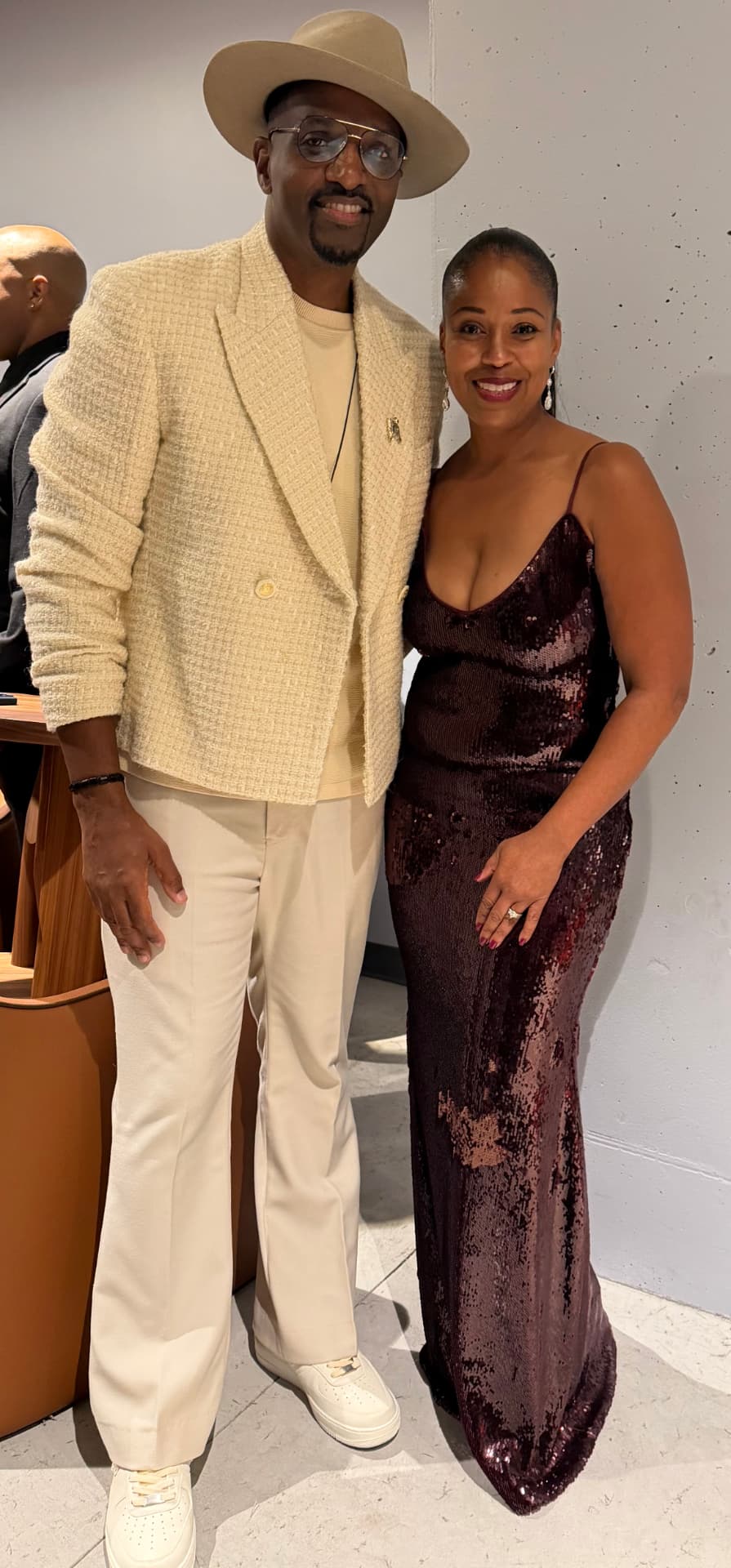 The guest artist in a cream suit posing with a guest in a sequined gown