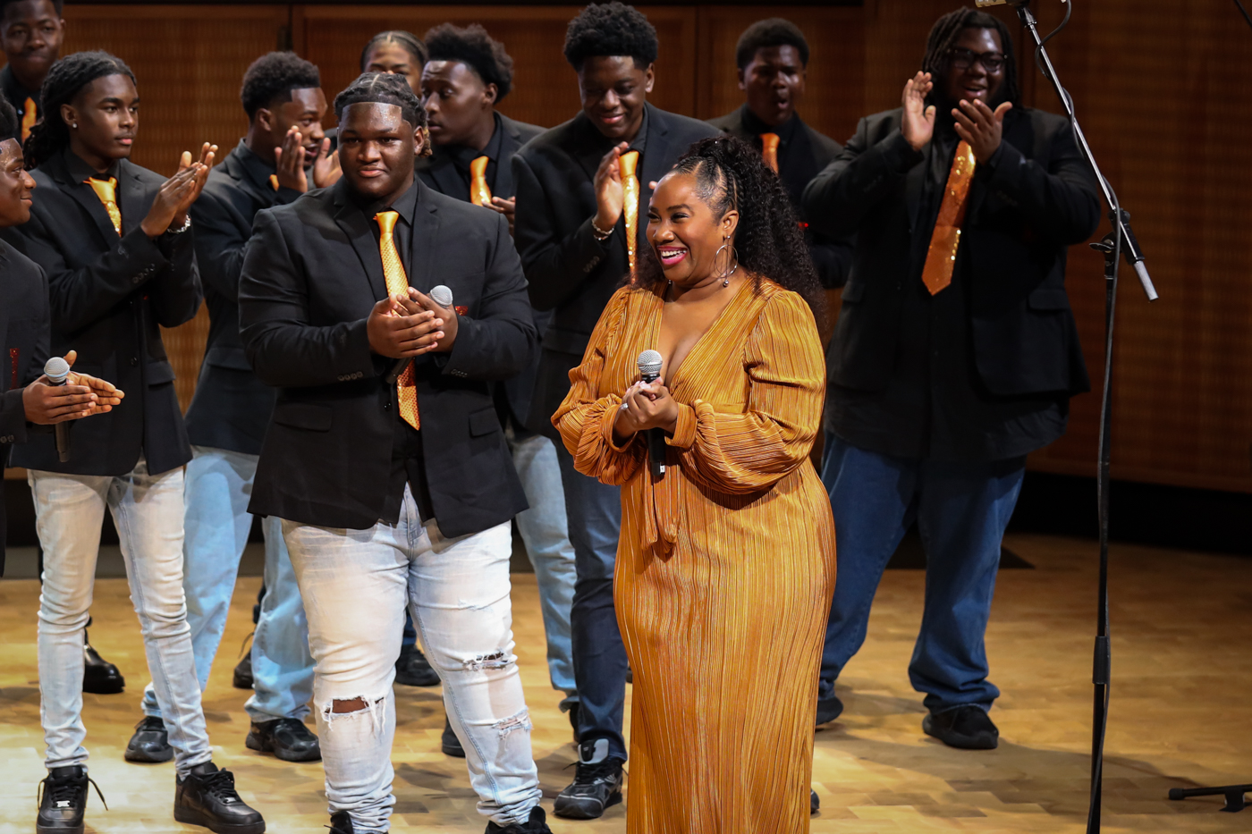 The choir applauding a smiling guest vocalist in a gold dress