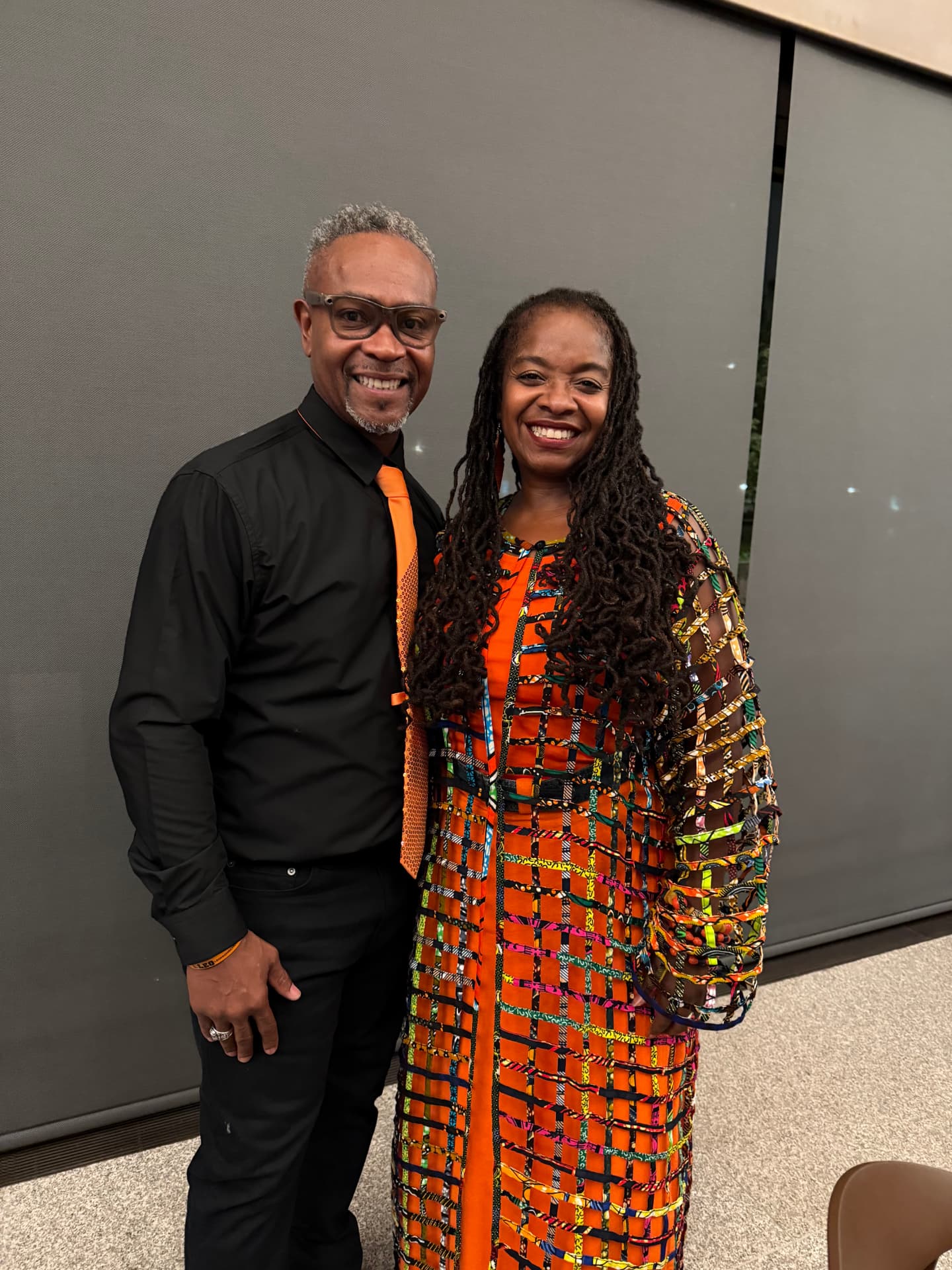 The choir director smiling with a guest in a vibrant orange dress
