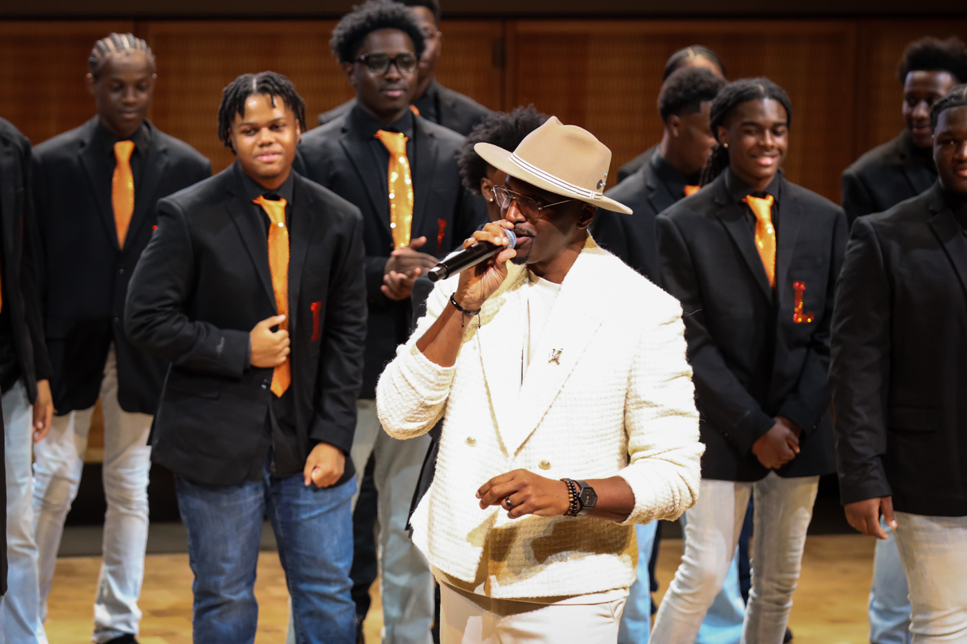 A guest vocalist in a white suit and hat singing with the choir