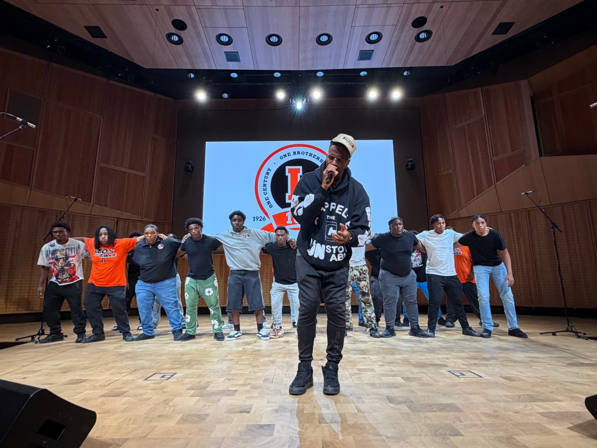 The choir linked arm in arm behind a guest vocalist during rehearsal