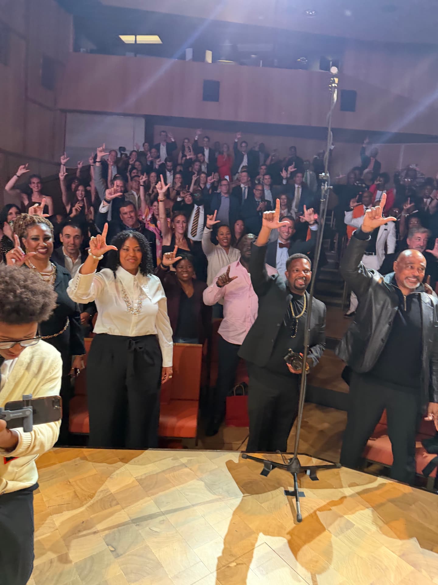 The audience on its feet throwing up the L sign, seen from the stage