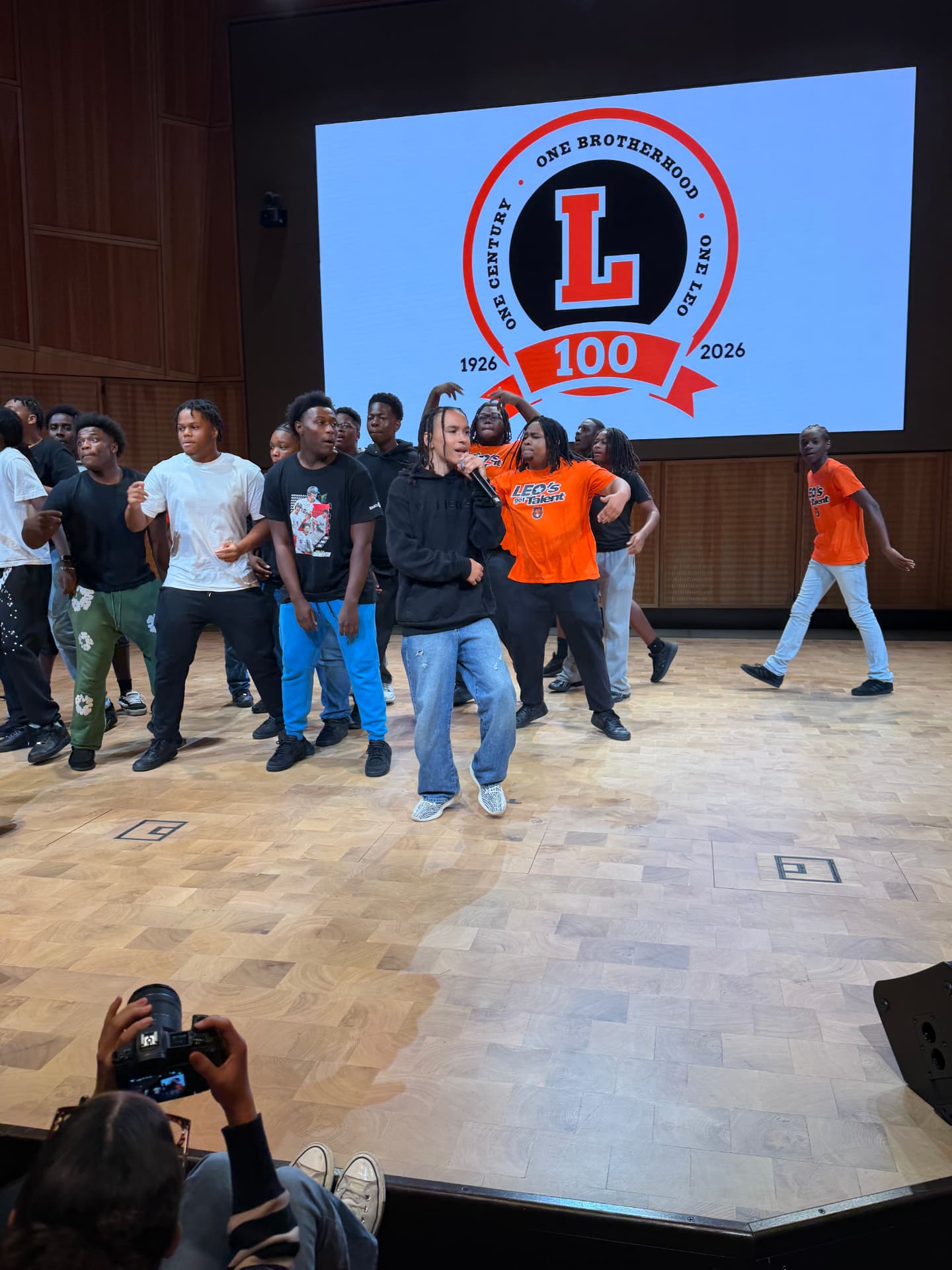 A guest artist singing as the choir moves together on stage in rehearsal