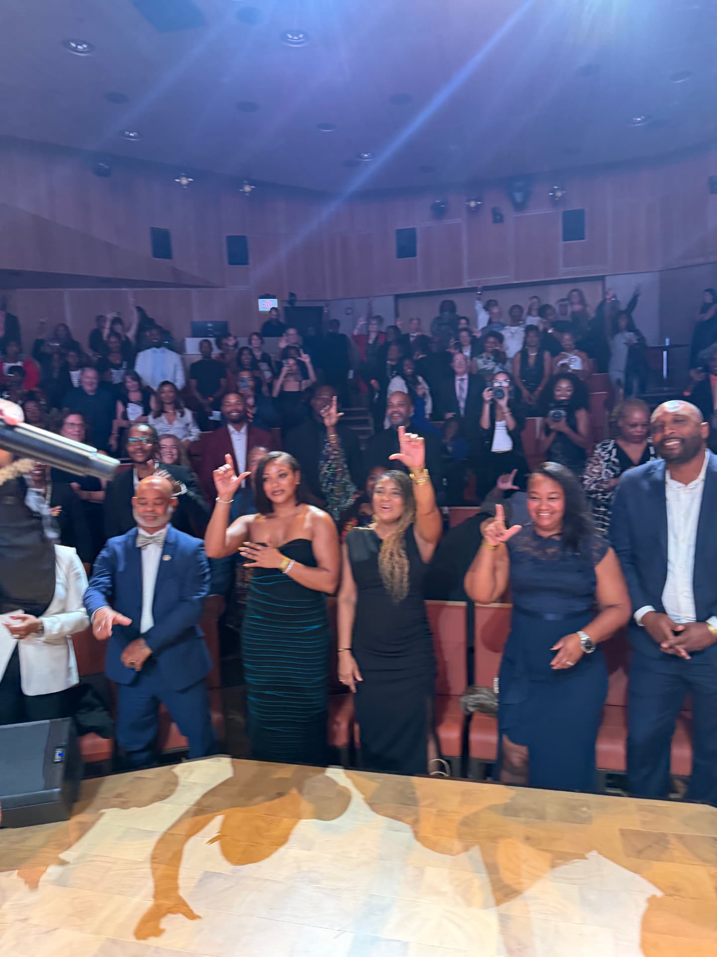 Guests standing and throwing up the L from the front row