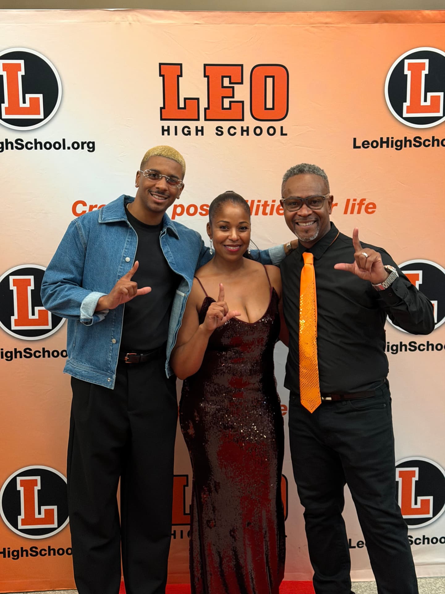 Three guests throwing up the L on the red carpet