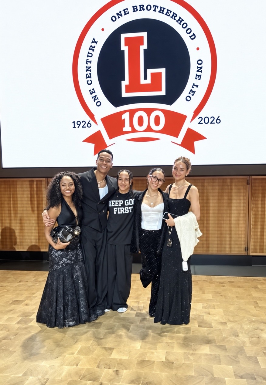 Guests posing beneath the Leo 100 centennial logo