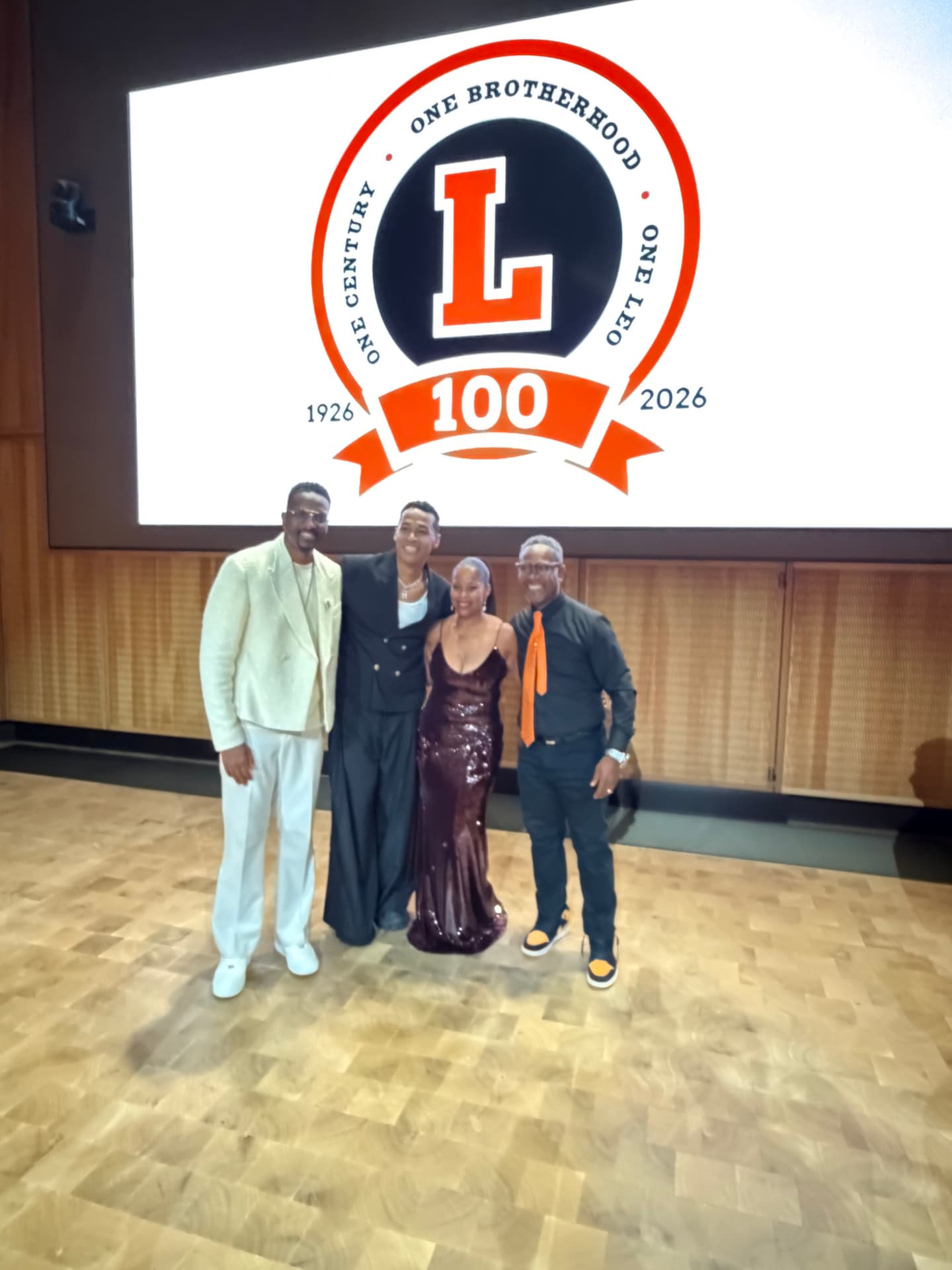 Four guests and performers posing on stage beneath the Leo 100 crest