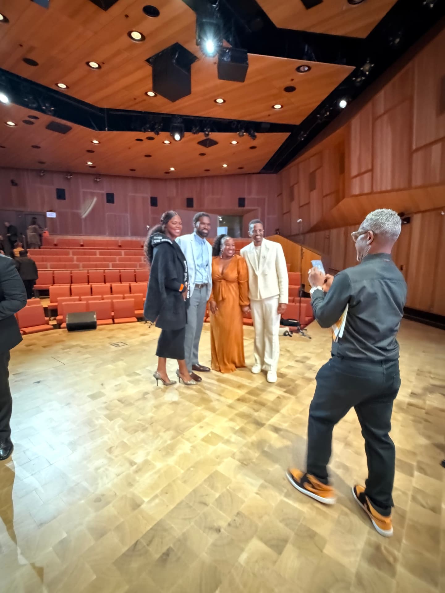 The choir director snapping a photo of guests on stage after the show