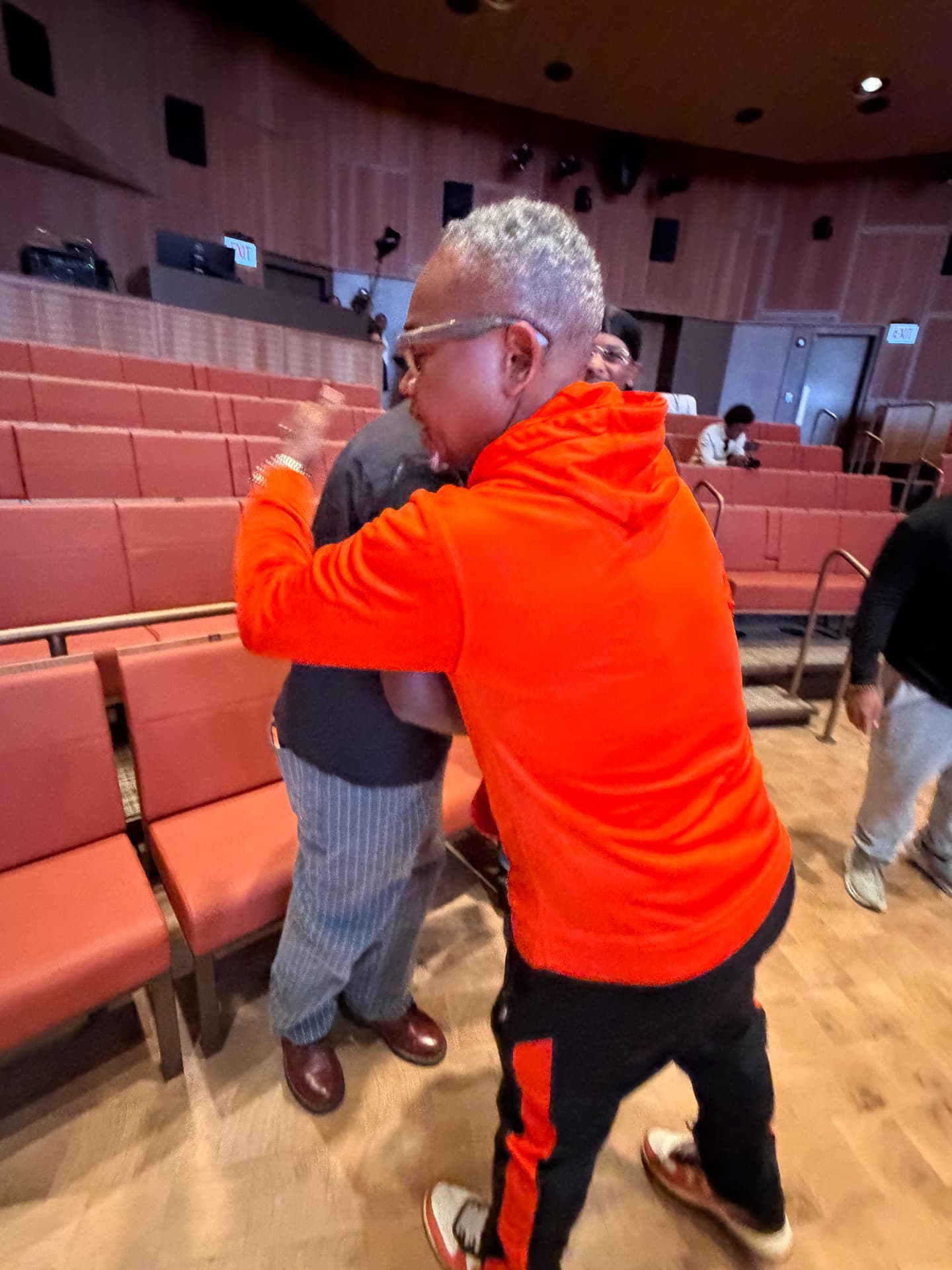 A warm hug between guests in the auditorium seats