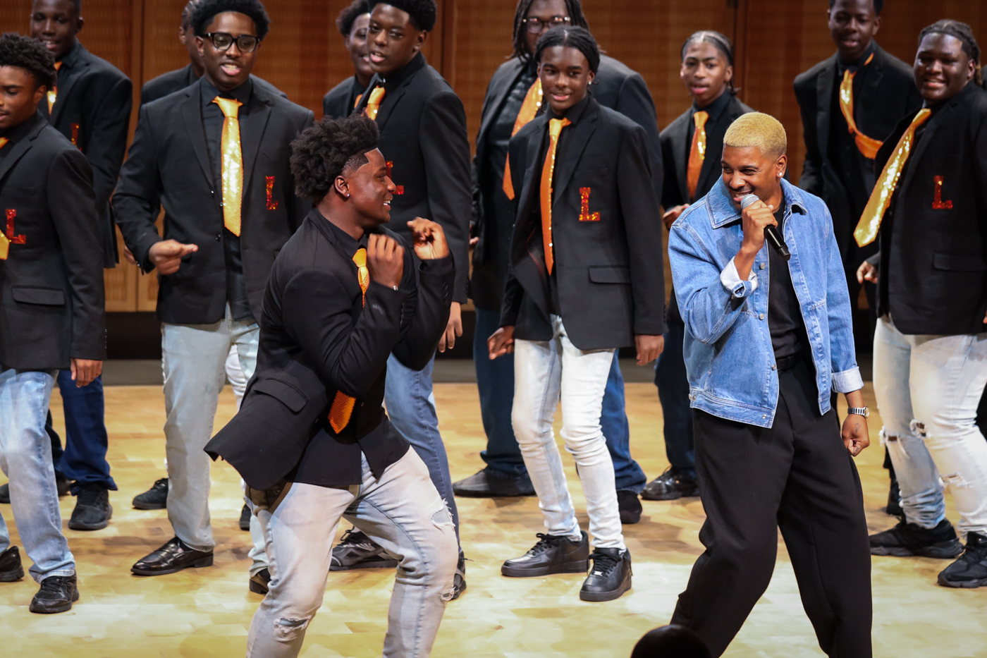 A choir member dancing alongside a guest vocalist in a denim jacket